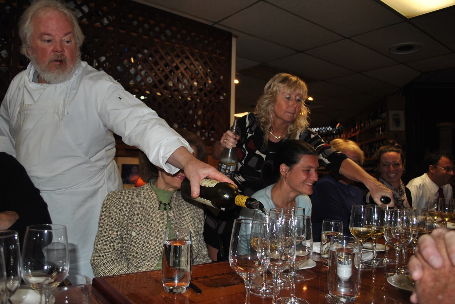 Bill Curtis pouring wine table-side at a winemaker dinner