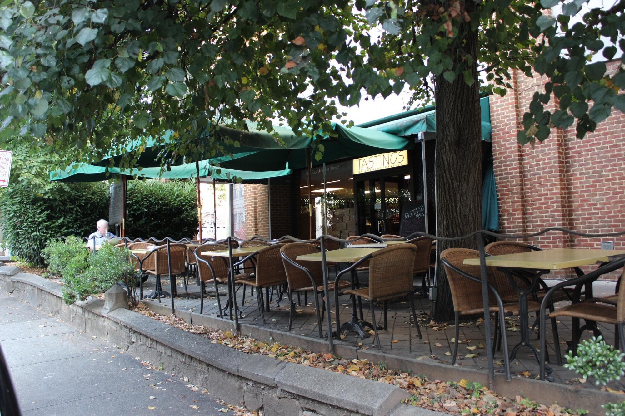 The sidewalk patio under the tree, green awnings reading Tastings, 502 East Market Street