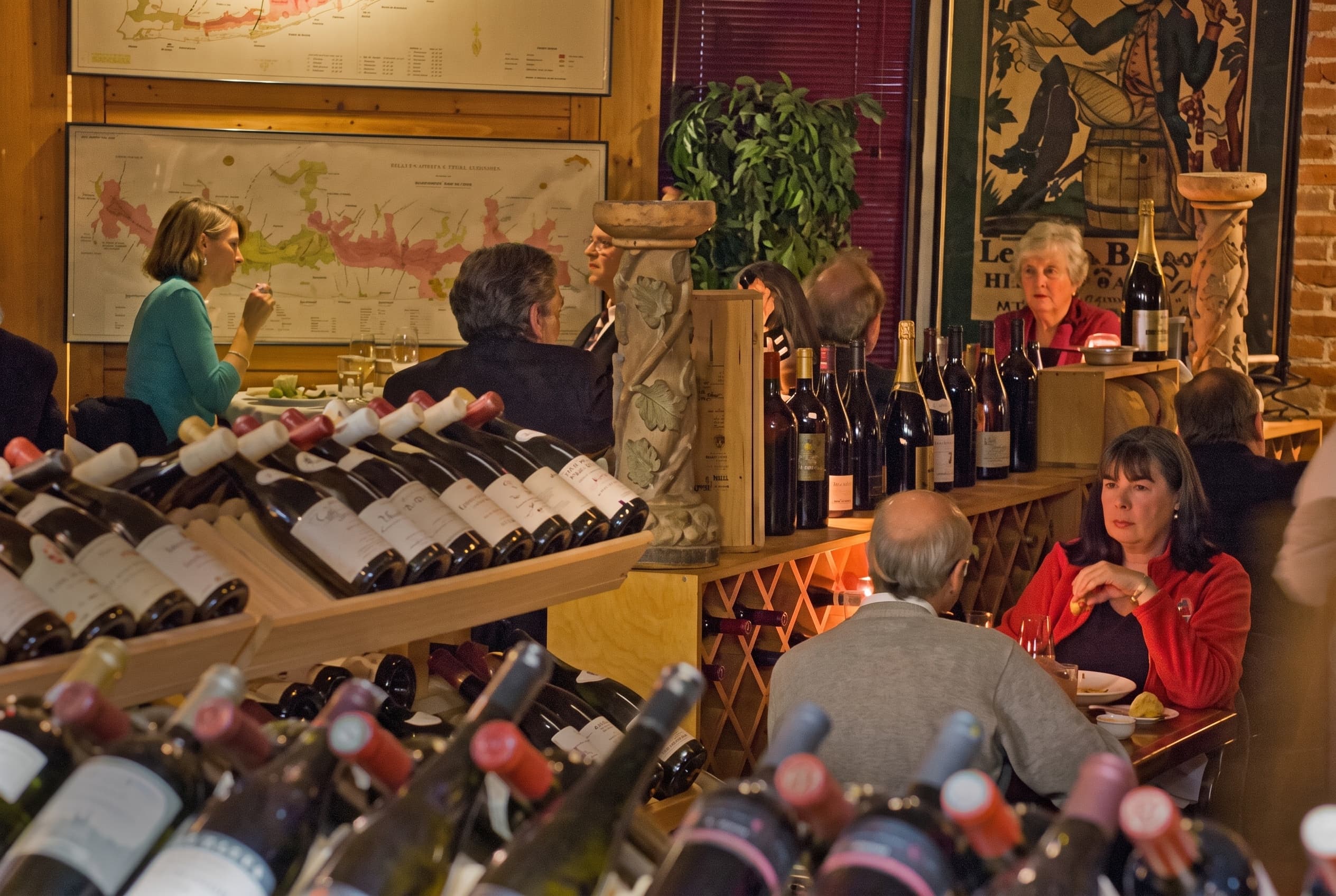 The Tastings room: wine racks in front, tables behind, Burgundy maps on the wall
